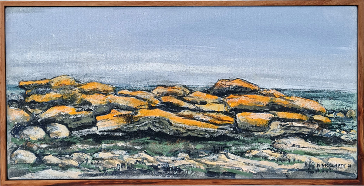 Landscape painting of yellow rocks against a blue sky, in a wooden frame
